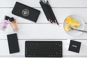 Black office stuff, colorful bottles and a cake on the white desk