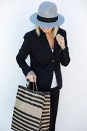 Smiling, blonde woman in suit and hat, with the shopping bag