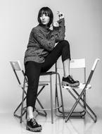 Black and white photo of the girl, posing on the chairs