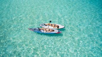 two girls sunbathe on boards on the sea surface