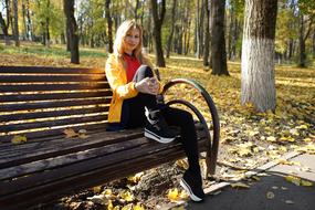 stylish young girl sits on Bench in Park at fall