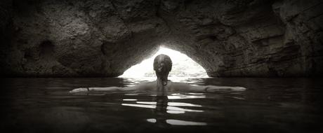 woman standing in water at Cave opening