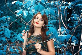Woman posing among the blue leaves