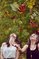 two young Girls playing with Autumn Leaves