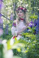 young girl in Russian Folk Costume posing among flowers