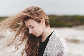 Profile portrait of the girl, with the hair in wind, with the closed eyes, on the landscape