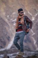 Bearded man in cap and sunglasses, with backpack, on the snowy mountain in Pakistan