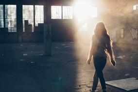 girl in the rays of the bright sun in an abandoned building