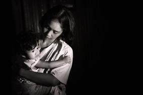 asian woman holding baby girl at darkness