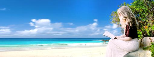 Blonde woman reading a book on the beautiful sandy beach with stones and plants