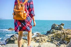 girl with a backpack on the rocks near the sea