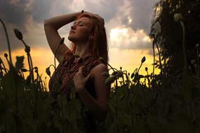 Girl sitting in Poppy field at Sunset