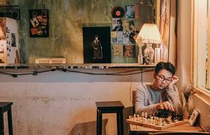 sad asian guy is playing chess