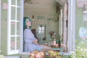 Portrait of green hair Girl sitting on window sill