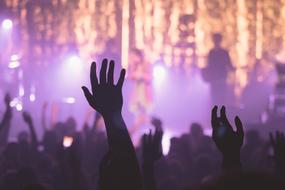 crowd of people with hands up in front of stage, concert