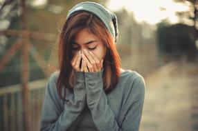 sad girl covers her face with her hands