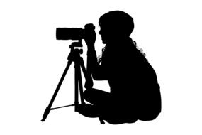 black silhouette of a woman with a camera on a stand