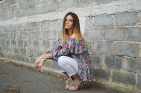 Woman with blonde and dark hair, posing near the stone wall