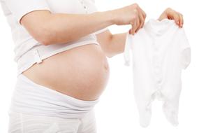 pregnant woman holds at belly bodysuit for baby