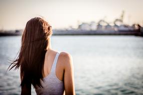 photo of a girl standing facing the ocean