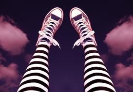 Wearing red shoes and black and white striped tights on colorful background