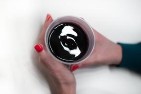 cup with Hot drink in female Hands with red polished Nails