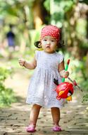 photo of cute asian girl with plastic toy in hand