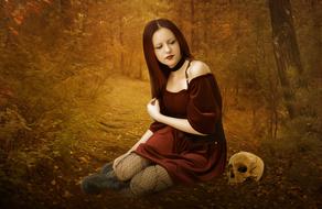 Gothic girl and human skull in forest