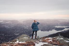 Back view of a blonde girl on the beautiful mountain, looking downside on the beautiful landsscape