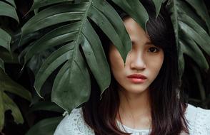 sad asian Girl beneath big leaves, Face portrait