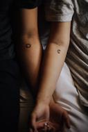 sun and moon tattoos on male and female arms
