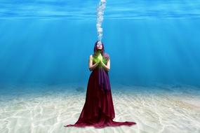 woman in long dress stands on seabed underwater, collage
