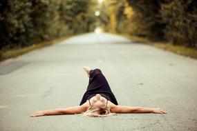 Girl in black dress laying on road