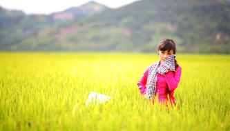 Asian Girl in red jacket posing on green field