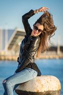 Portrait of the smiling and posing woman in sunglasses, on the coast