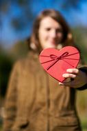 Valentineâs Day Celebration, happy girl with red heart in stretched hand outdoor