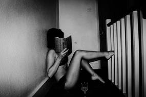 black and white photo of a girl sitting on the floor with a book