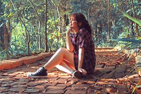 happy girl sits on path in forest