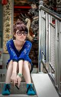 Beautiful girl in the blue clothing and glasses, posing on the stairs