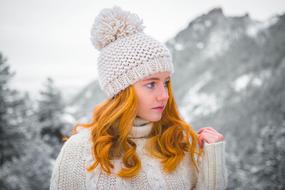 redhead Woman in knitted hat and sweater at winter landscape