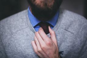 Man with the beard, holding hand on the necktie