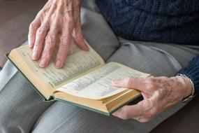 open Book in hands of elderly person
