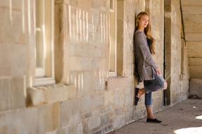 pretty Young girl in casual clothing leaning on wall