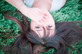 Portrait of the girl, laying on the green grass