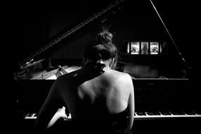 black and white photo of a girl playing the piano