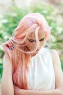 Woman with pink hair on green blurred background with the plants