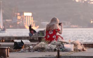 Woman taking photo with smartphone in front of sea at Sunset