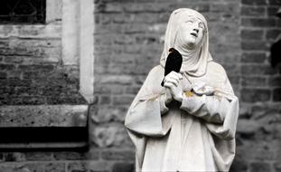 Black and white photo of the blackbird on hand of praying Nun sculpture