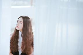 asian girl with long hair sitting on the background of white curtains