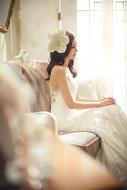 young girl in Wedding Dress sits on sofa